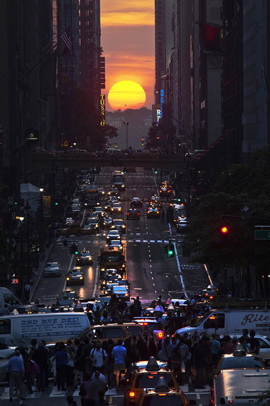 People take pictures of sunset on 42nd street, during the "Manhattanhenge"in New York City