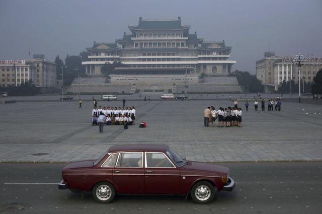 A car passes by as students tour Kim Il Sung Square in Pyongyang, Nor