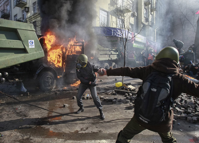 Anti-government protesters throw stones towards Interior Ministry officers during a rally near the building of Ukraine's house of parliament in Kiev