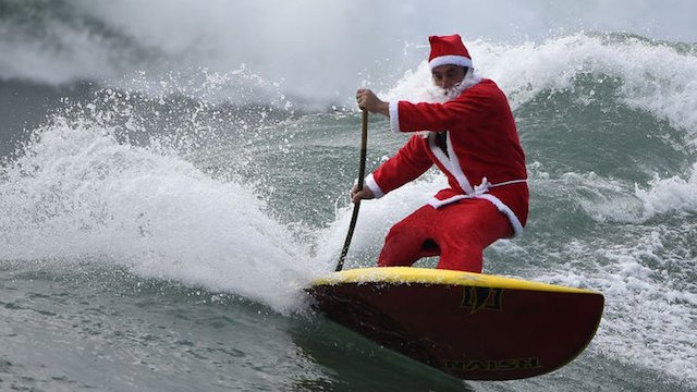 Hombre vestido de Santa Claus participa en el concurso "Stand Up Paddle"