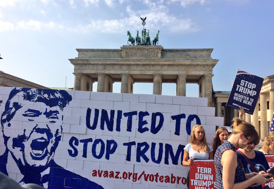 Activistas derriban un muro de cartón en Alemania e invitan a los estadounidenses que viven en ese país a votar en contra de Trump