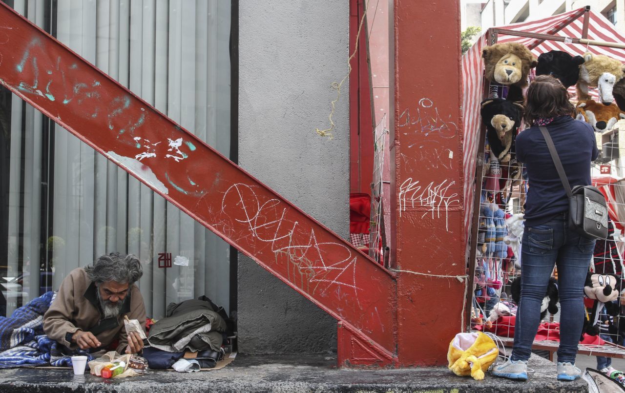 MÉXICO, D.F., 17OCTUBRE2015.- Mientras una comerciante dispone su puesto de peluches para comenzar la venta, una persona en situación de calle reúne algunos víveres que transeúntes le han dado para comenzar el día con el estómago lleno. La población callejera ha ido aumento en la ciudad, según un informe del gobierno capitalino se tiene un registro de 5 mil 600 personas en dicha situación. La delegación Cuauhtémoc es uno de las que cuentan con mayor índice de personas en situación de calle. 