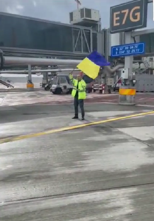 Empleado de aeropuerto da indicaciones a avión ruso con bandera de Ucrania