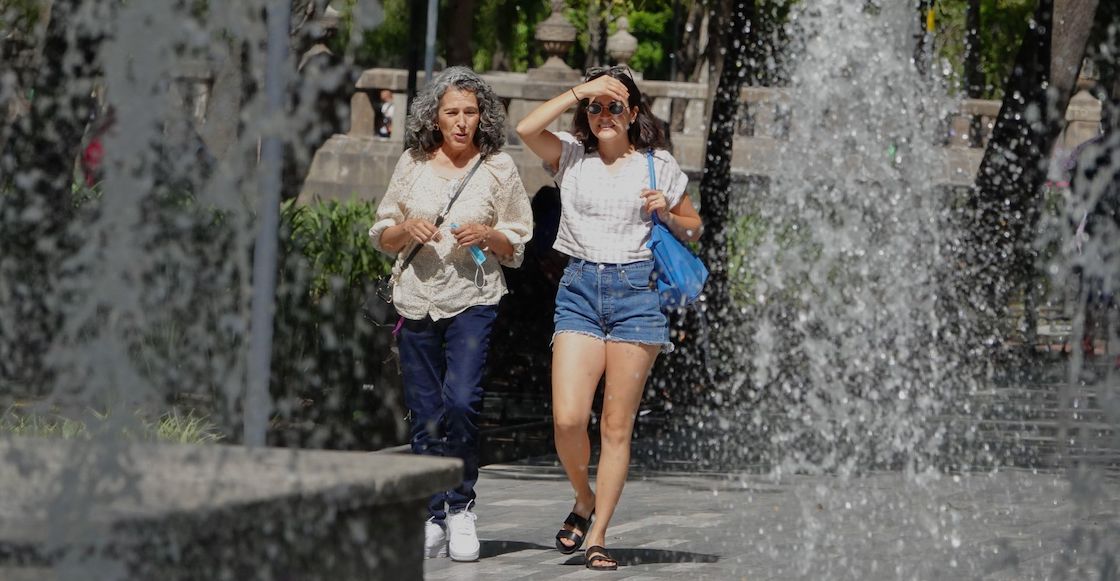 Dos personas caminando detrás de una fuente