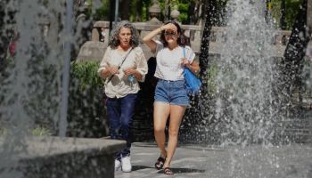 Dos personas caminando detrás de una fuente