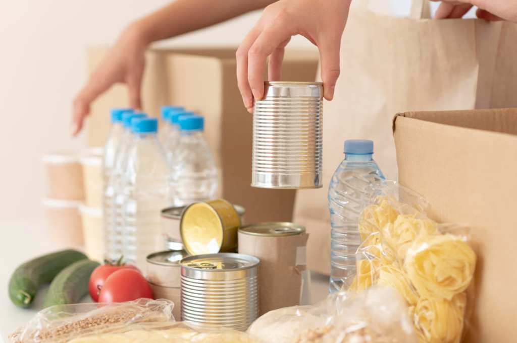 Voluntarios poniendo comida enlatada en caja