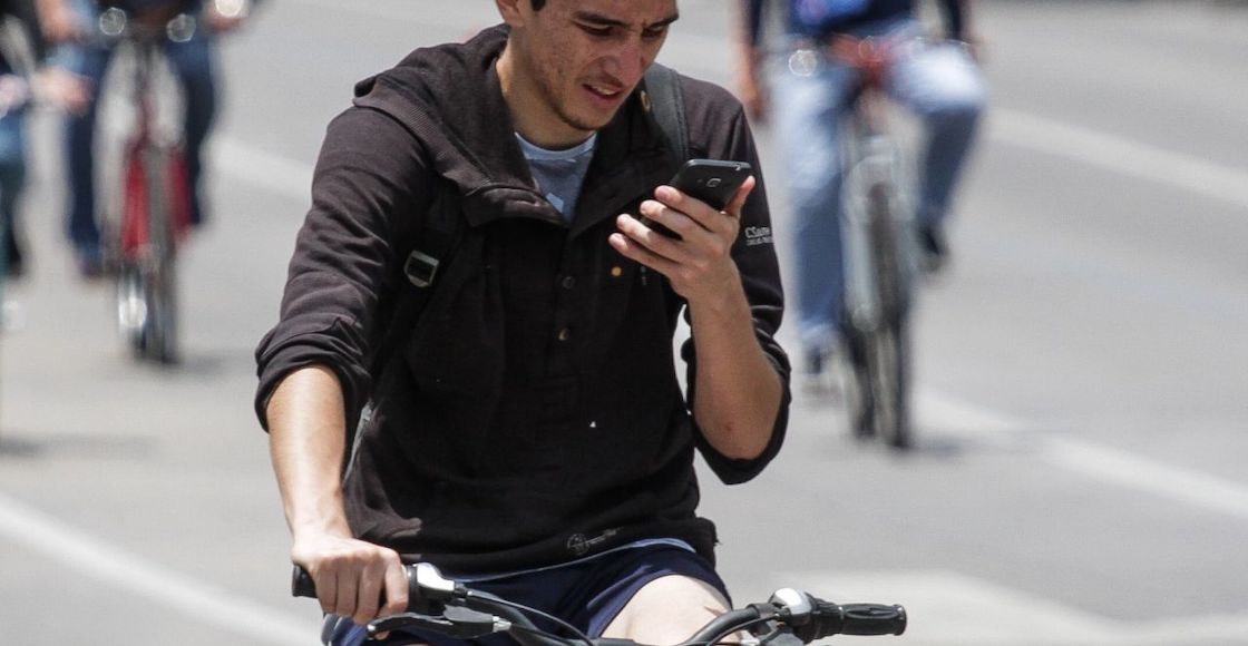 Joven ve su celular mientras maneja su bicicleta