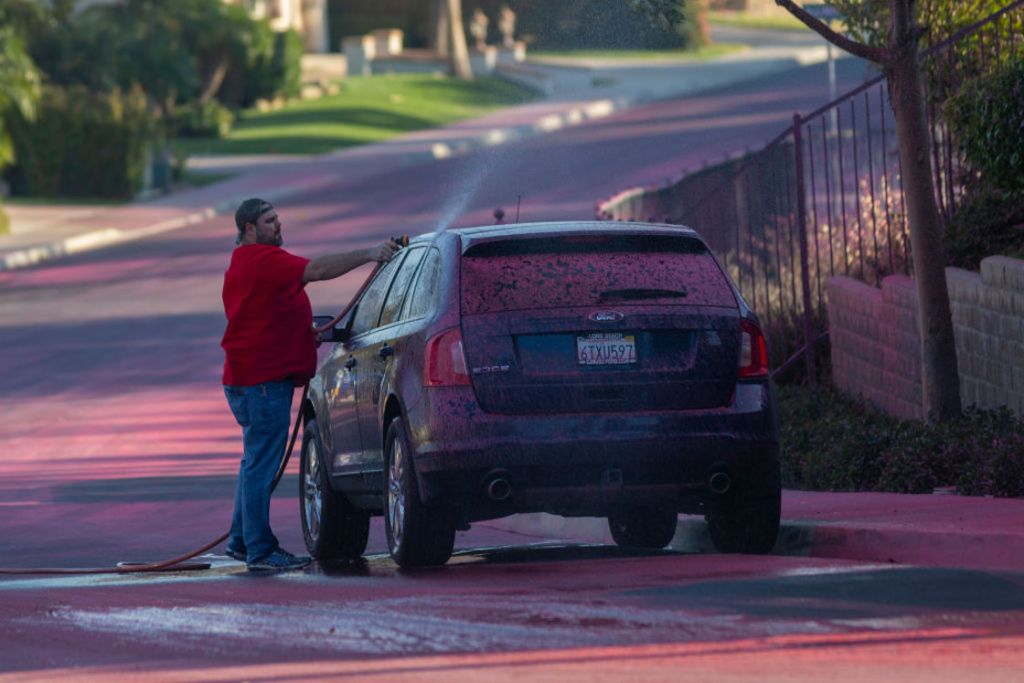 Personas tienen que lavar sus coches luego de que cae el polvo rosa.